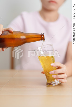 woman pour Beer into a glass on table, suffering from alcohol addiction, alcoholism concept. depicting emotional distress, depression, substance abuse problem, unhealthy lifestyle and mental health woman pour Beer into a glass on table, suffering from alcohol addiction, alcoholism concept. depicting emotional distress, depression, substance abuse problem, unhealthy lifestyle and mental health 137755157