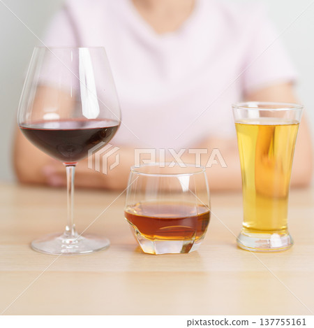 variety of alcohol drinks including glass of wine, beer, whiskey or cognac on table with woman background. celebration, alcoholism, thinking about choosing a drink and unhealthy lifestyle concept 137755161