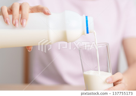 Healthy woman pouring fresh milk into glass at home, female drinking for calcium and strong bones, high protein, dairy product for healthy lifestyle, wellness and daily routine concept Healthy woman pouring fresh milk into glass at home, female drinking for calcium and strong bones, high protein, dairy product for healthy lifestyle, wellness and daily routine concept 137755173