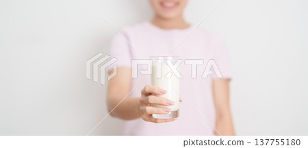 Healthy woman holding glass of fresh milk at home, female drinking milk for calcium and strong bones, high protein, dairy product for healthy lifestyle, wellness and daily routine concept 137755180