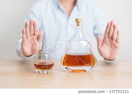 Man making stop hand gesture to refuse a glass of Cognac, Healthy man say no to alcohol drink, stop alcoholism and addiction concept. Responsible man reject a drink before driving and quit booze Man making stop hand gesture to refuse a glass of Cognac, Healthy man say no to alcohol drink, stop alcoholism and addiction concept. Responsible man reject a drink before driving and quit booze 137755211