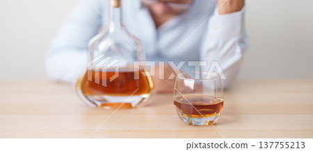 Stressed man drinking cognac alone with problem. Exhausted drunk man looking stressed and sleepy. Alcohol addiction, Alcoholism, emotional distress and mental health concept Stressed man drinking cognac alone with problem. Exhausted drunk man looking stressed and sleepy. Alcohol addiction, Alcoholism, emotional distress and mental health concept 137755213