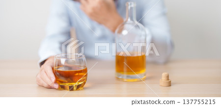 Stressed man drinking whiskey alone with problem. Exhausted drunk man looking stressed and sleepy. Alcohol addiction, Alcoholism, emotional distress and mental health concept Stressed man drinking whiskey alone with problem. Exhausted drunk man looking stressed and sleepy. Alcohol addiction, Alcoholism, emotional distress and mental health concept 137755215