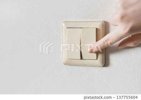 Hand pressing an electrical wall switch controlling energy and power Hand pressing an electrical wall switch controlling energy and power 137755604