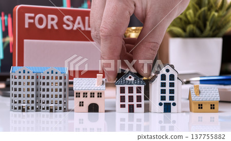 Hand Choosing House Model in For Sale Property Market Scene 137755882