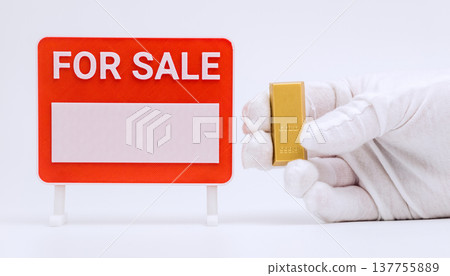 For Sale Sign and Gold Bar in Gloved Hand on White 137755889