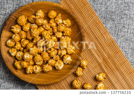 Bowl of popcorn on a wooden plate placed on a textured surface Bowl of popcorn on a wooden plate placed on a textured surface 137756210