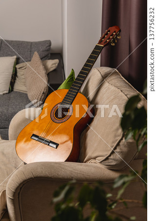 Guitar rests on a sofa in a cozy living room during daylight hours 137756232