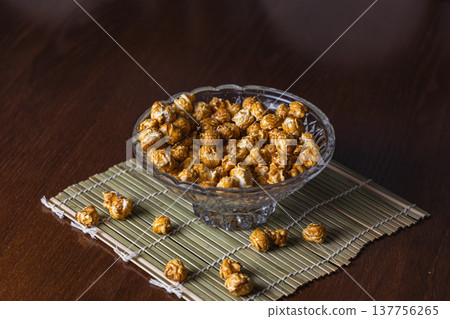 Sweet popcorn in a glass bowl on a bamboo mat at home Sweet popcorn in a glass bowl on a bamboo mat at home 137756265
