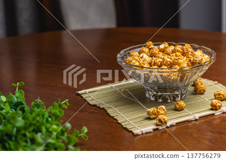 Popcorn in a clear bowl placed on a bamboo mat on a wooden table Popcorn in a clear bowl placed on a bamboo mat on a wooden table 137756279