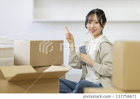 一位微笑的年輕女子坐在被紙箱包圍的座位上,直視鏡頭。 (圖片來源:Moving) 一位微笑的年輕女子坐在被紙箱包圍的座位上,直視鏡頭。 (圖片來源:Moving) 137756671