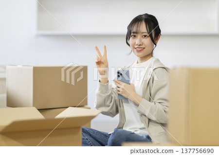 一位微笑的年輕女子坐在被紙箱包圍的座位上,直視鏡頭。 (圖片來源:Moving) 一位微笑的年輕女子坐在被紙箱包圍的座位上,直視鏡頭。 (圖片來源:Moving) 137756690