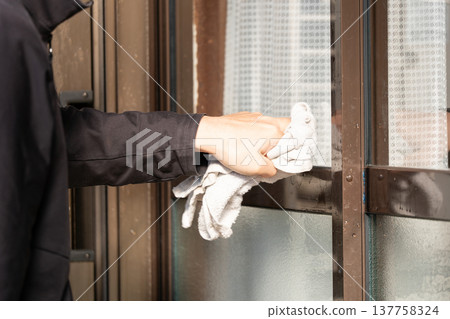 A worker wiping aluminum window frames with a rag. A worker wiping aluminum window frames with a rag. 137758324