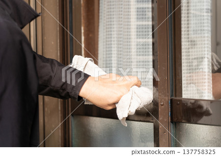 一名工人正在用抹布擦拭鋁合金窗框。 一名工人正在用抹布擦拭鋁合金窗框。 137758325