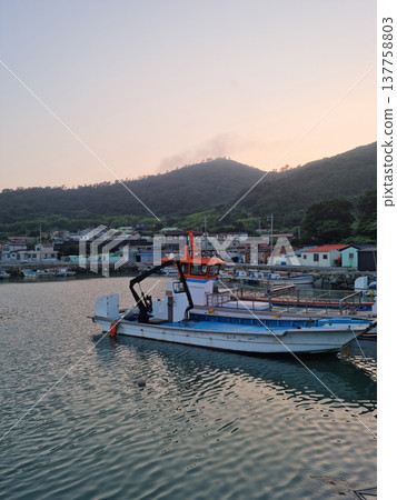 It is a landscape of an island village with fishing boats.	 137758803