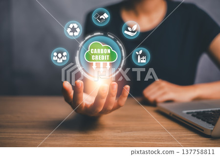 Hand holding digital carbon credit icons symbolizing sustainable business practices and environmental responsibility. 137758811