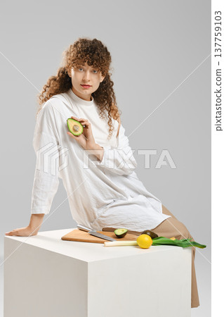 Young woman holds half of avocado Young woman holds half of avocado 137759103