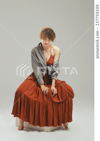 Cute young woman in sundress and shirt sits in studio Cute young woman in sundress and shirt sits in studio 137759108