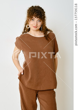 Stylish woman poses in casual brown outfit against plain background Stylish woman poses in casual brown outfit against plain background 137759118