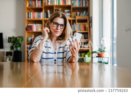 Woman using smartphone while taking a break and checking messages. Woman using smartphone while taking a break and checking messages. 137759283