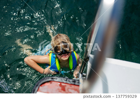 Child snorkeling near boat during tropical family vacation. Child snorkeling near boat during tropical family vacation. 137759329