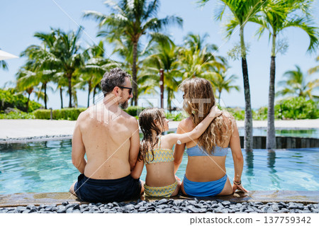 Family relaxing by tropical resort pool, child with diabetes wears glucose monitor. Family relaxing by tropical resort pool, child with diabetes wears glucose monitor. 137759342