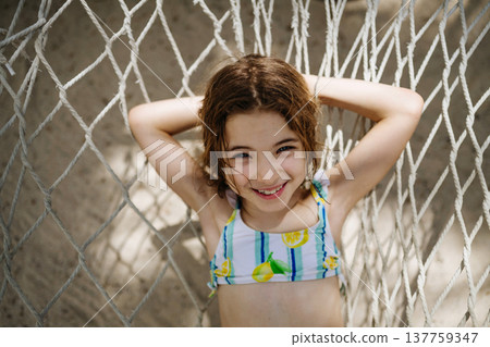 Smiling girl relaxing in hammock during tropical family vacation. Smiling girl relaxing in hammock during tropical family vacation. 137759347