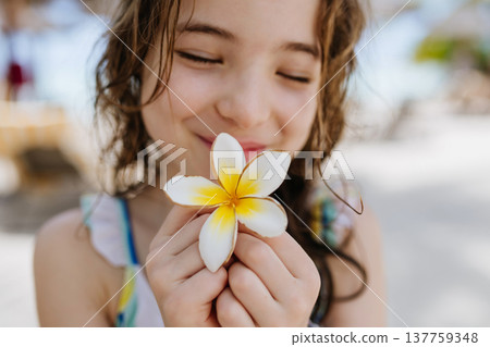 Happy child smelling tropical flower during family vacation at beach resort. 137759348