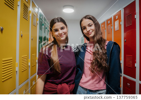 Teen students hanging out in school hallway by lockers. Teen students hanging out in school hallway by lockers. 137759365