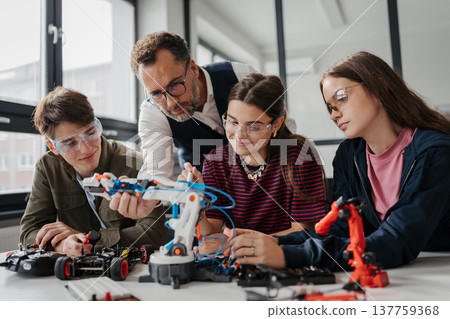 High school students working on robotics project with their teacher. 137759368
