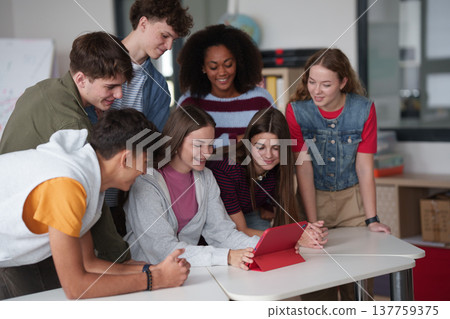 Teen students learning together with digital tablet in modern classroom. 137759375