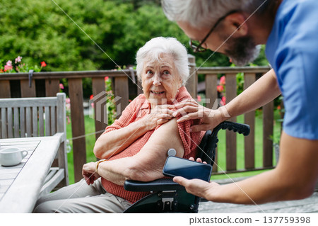 Home nurse checking glucose level of senior lady with smartphone. Home nurse checking glucose level of senior lady with smartphone. 137759398