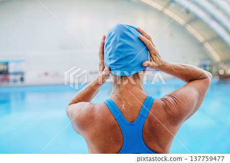 Rear view of older woman getting ready for swim. Rear view of older woman getting ready for swim. 137759477
