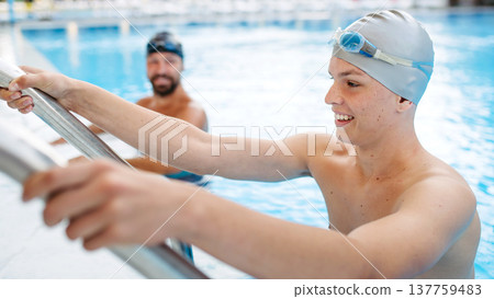 Father and teenage son enjoying swim training together. Father and teenage son enjoying swim training together. 137759483