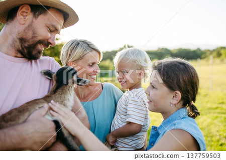 Family petting little goat at farm. 137759503