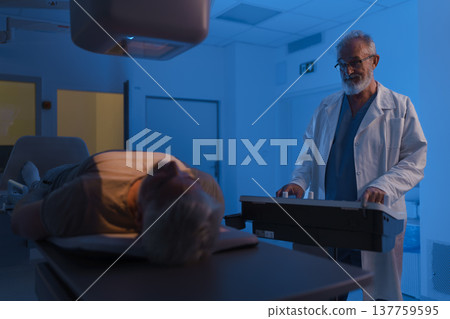 Male patient undergoing X-ray examination using tilting radiographic wall stand. 137759595