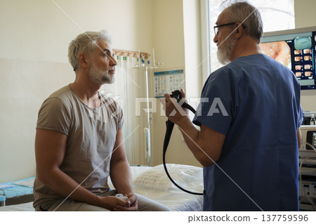 Doctor explaining colonoscopy results to patient using monitor images. Doctor explaining colonoscopy results to patient using monitor images. 137759596