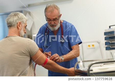 Older doctor drawing blood from patient's arm. 137759616
