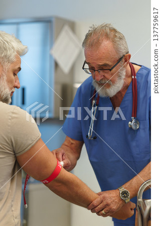 Older doctor drawing blood from patient's arm. Older doctor drawing blood from patient's arm. 137759617