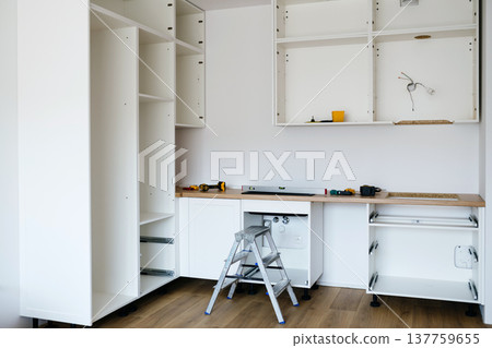Installing kitchen cabinets during modern kitchen renovation. 137759655