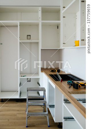 Installing kitchen cabinets during modern kitchen renovation. 137759659