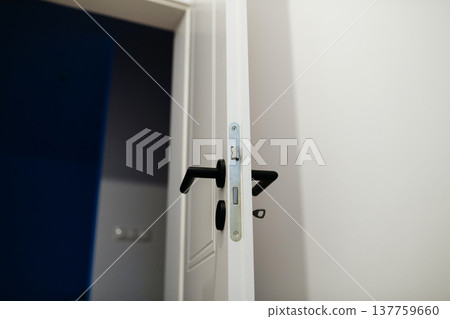 Installing door hardware and handle on interior door during home renovation. Installing door hardware and handle on interior door during home renovation. 137759660
