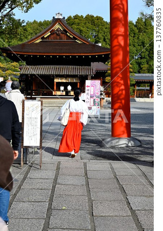 A shrine maiden passing through the torii gate of a shrine. A shrine maiden passing through the torii gate of a shrine. 137760835