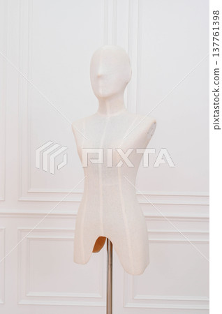 Elegant white mannequin bust on stand in shop. poised female torso form for fashion display. body of dummy figure stands against classic wall Elegant white mannequin bust on stand in shop. poised female torso form for fashion display. body of dummy figure stands against classic wall 137761398