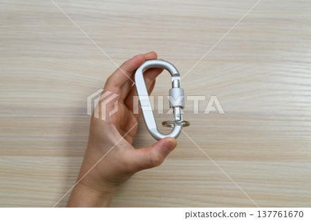 A silver screw-lock carabiner held in the hand A silver screw-lock carabiner held in the hand 137761670