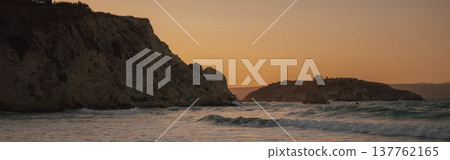 Golden orange sunset sky over ocean waves near steep coastal cliff and rocky island landscape view Golden orange sunset sky over ocean waves near steep coastal cliff and rocky island landscape view 137762165