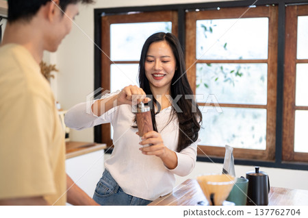 Asian couple making coffee a woman holding grinder aside man standing at cooking counter in kitchen. Asian couple making coffee a woman holding grinder aside man standing at cooking counter in kitchen. 137762704