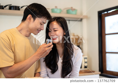 Asian man and woman couple smelling aroma from powder in grinder while making coffee in the kitchen. Asian man and woman couple smelling aroma from powder in grinder while making coffee in the kitchen. 137762709