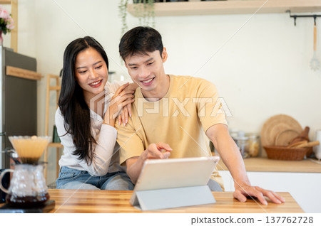 Asian man and woman couple watching video on tablet as making drip coffee at kitchen cooking counter 137762728
