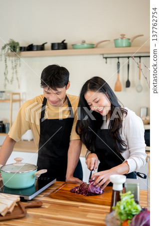 Asian couple woman girlfriend cutting vegetable as man boiling water cooking food at kitchen counter Asian couple woman girlfriend cutting vegetable as man boiling water cooking food at kitchen counter 137762754